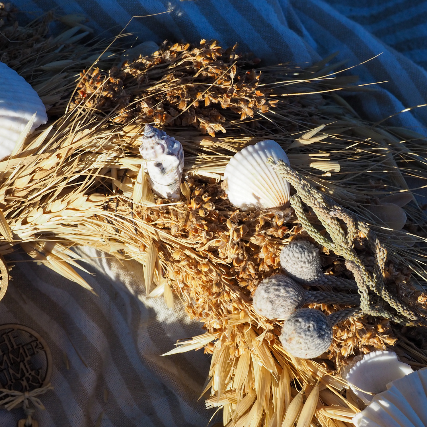 Naturalny wianek z suszonych traw i muszelek morskich THE SUMMER TIME Dream SEA leżacy na ręczniku plażowym